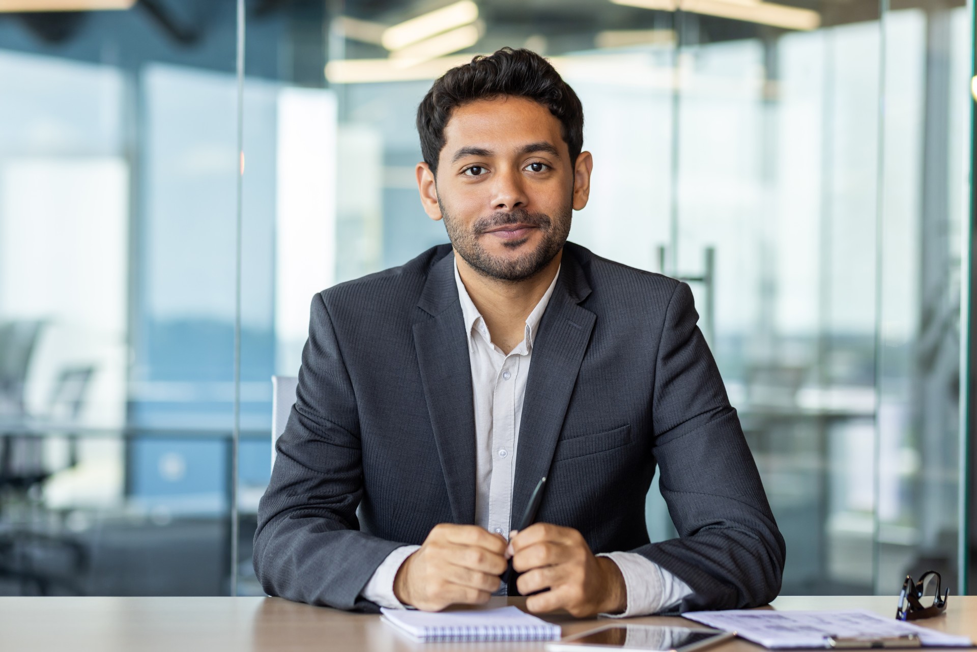 Portrait of a young investor banker at the workplace inside the bank office, a businessman in a business suit looking friendly at the camera, a man at work